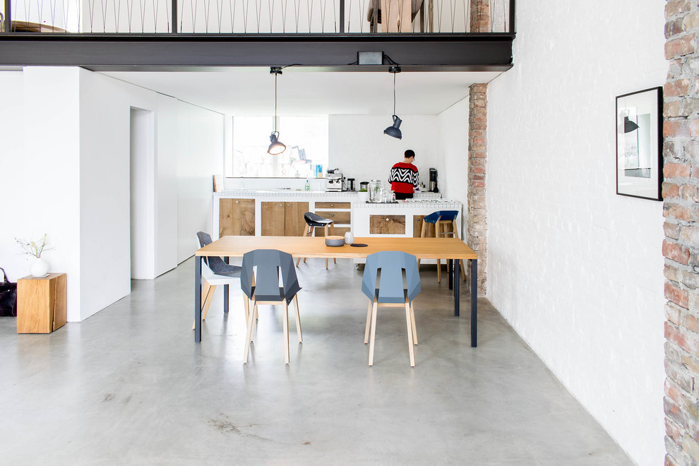Große Industrial Wohnküche ohne Kamin mit weißer Wandfarbe, Betonboden und grauem Boden in Berlin