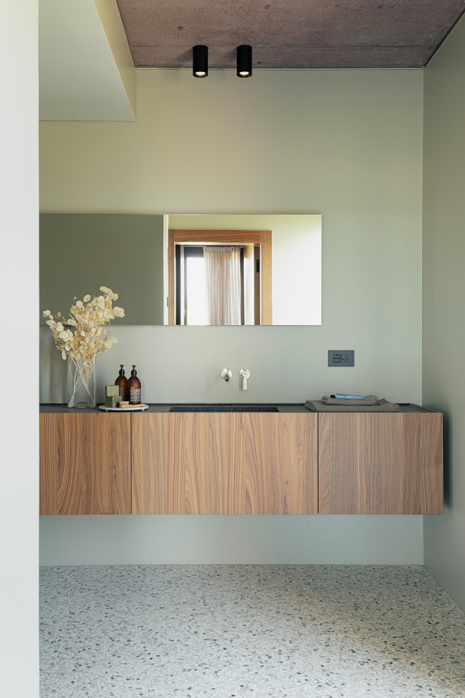 Стильный дизайн: ванная комната среднего размера в современном стиле с фасадами с декоративным кантом, светлыми деревянными фасадами, душем без бортиков, инсталляцией, зеленой плиткой, зелеными стенами, полом из терраццо, душевой кабиной, накладной раковиной, столешницей из известняка, разноцветным полом, открытым душем, черной столешницей, тумбой под одну раковину и подвесной тумбой - последний тренд