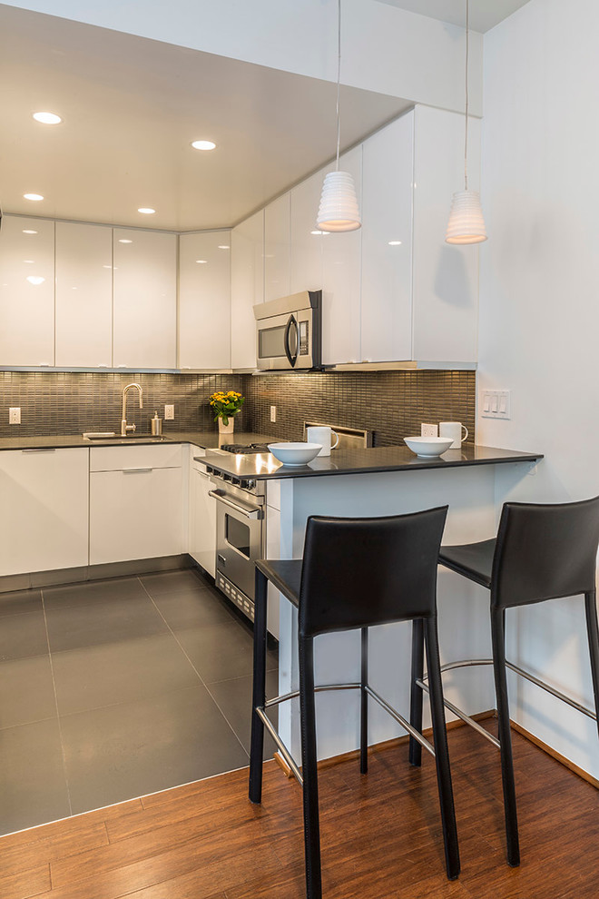 Contemporary kitchen in New York with flat-panel cabinets, white cabinets, grey splashback and stainless steel appliances.