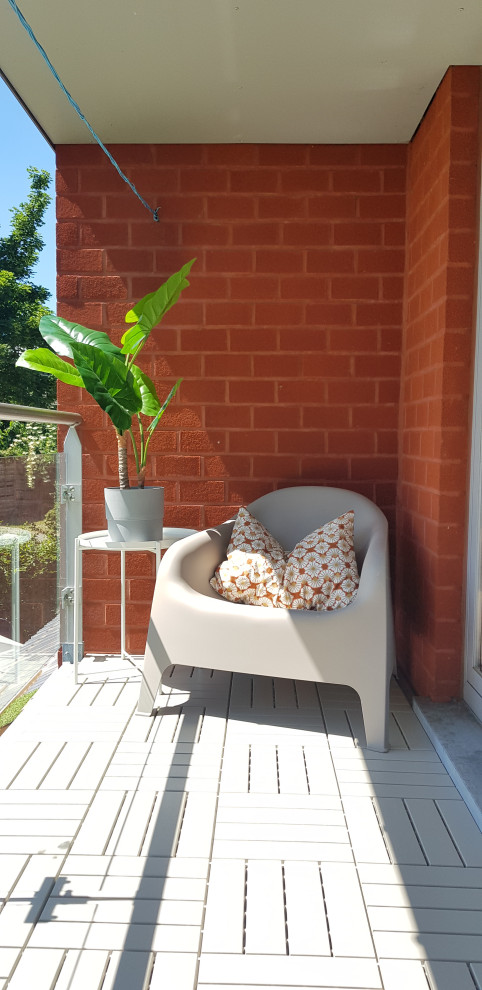 Cette image montre un petit balcon minimaliste d'appartement avec une extension de toiture et garde-corps.