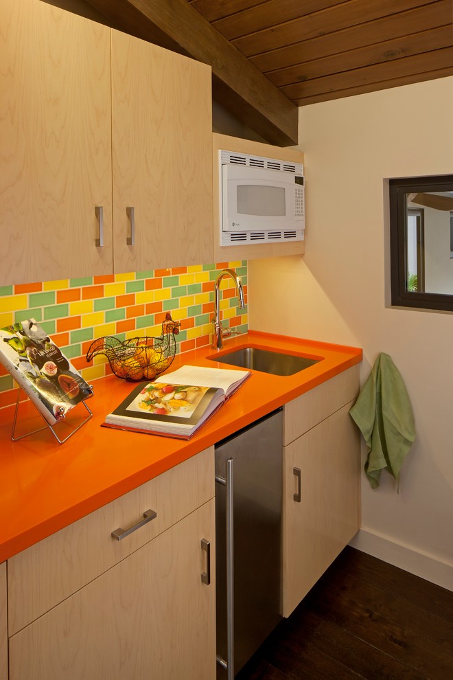 This is an example of a small midcentury single-wall separate kitchen in Los Angeles with an undermount sink, flat-panel cabinets, light wood cabinets, solid surface benchtops, multi-coloured splashback, ceramic splashback, stainless steel appliances, dark hardwood floors and orange benchtop.