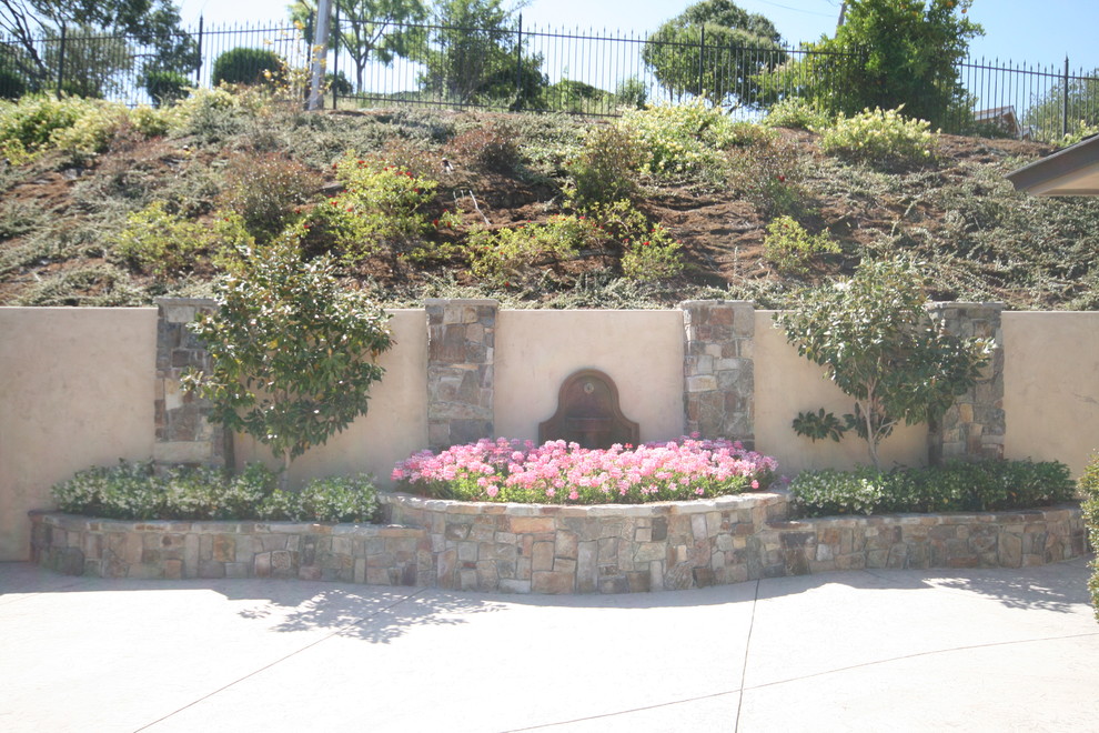 This is an example of a large mediterranean sloped garden for summer in San Francisco with natural stone pavers.