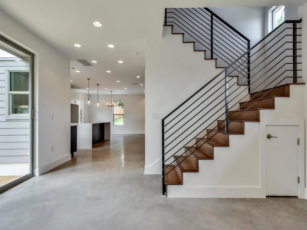 This is an example of a large modern wood u-shaped staircase in Austin with wood risers and metal railing.