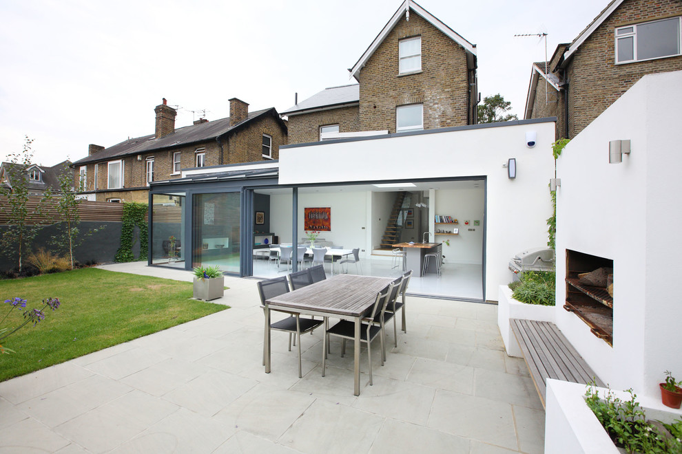 Contemporary backyard patio in London with a fire feature and concrete slab.