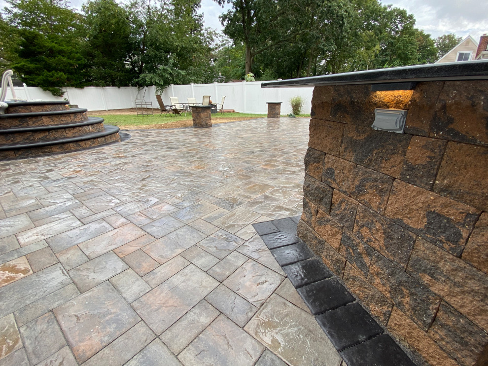 Photo of a large modern backyard patio in New York with an outdoor kitchen and concrete pavers.