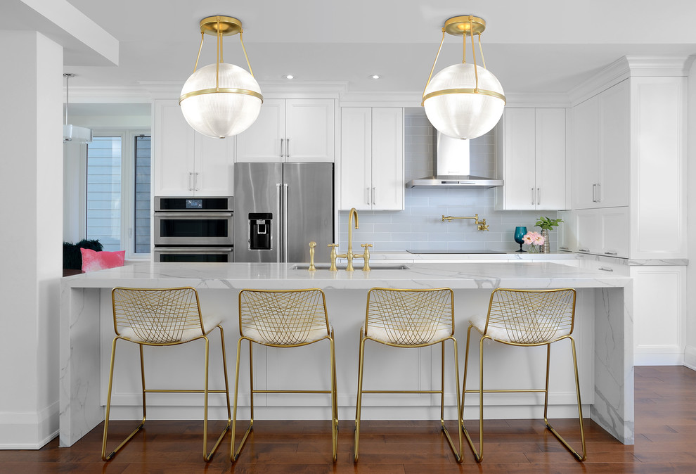Inspiration for a transitional galley dark wood floor and brown floor kitchen remodel in Toronto with an undermount sink, shaker cabinets, white cabinets, quartz countertops, gray backsplash, stainless steel appliances, an island and gray countertops