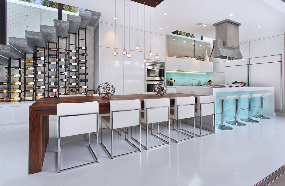 This is an example of a contemporary eat-in kitchen in Orange County with flat-panel cabinets, panelled appliances, wood benchtops and glass sheet splashback.