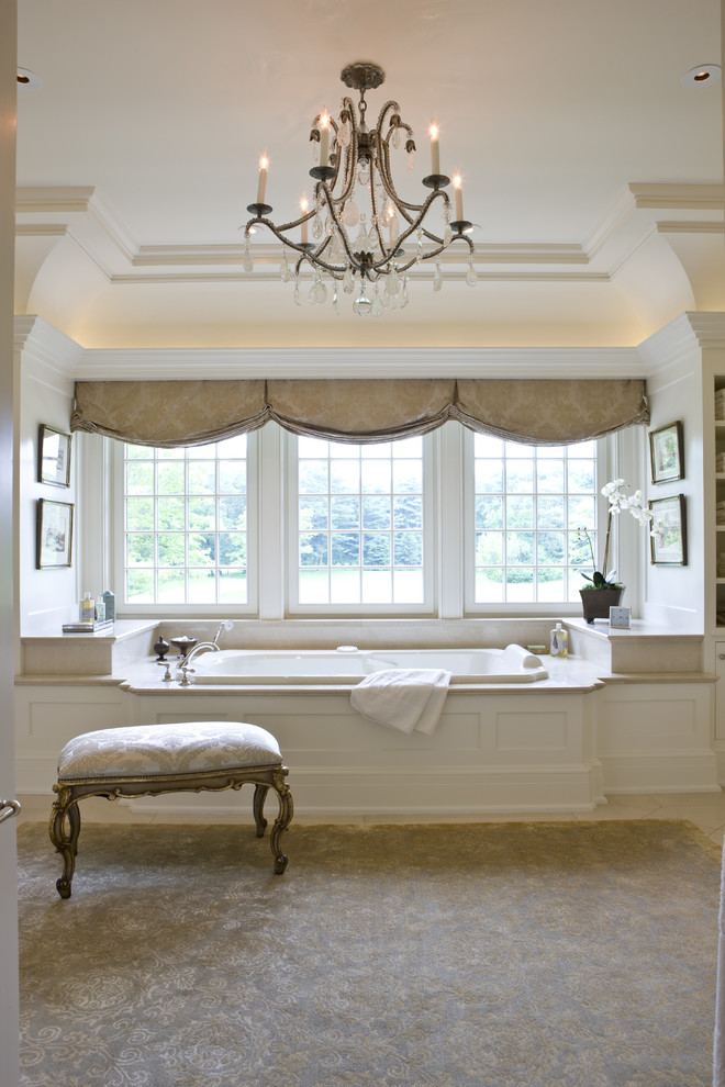 Traditional bathroom in Boston with white cabinets, a drop-in tub and beige tile.