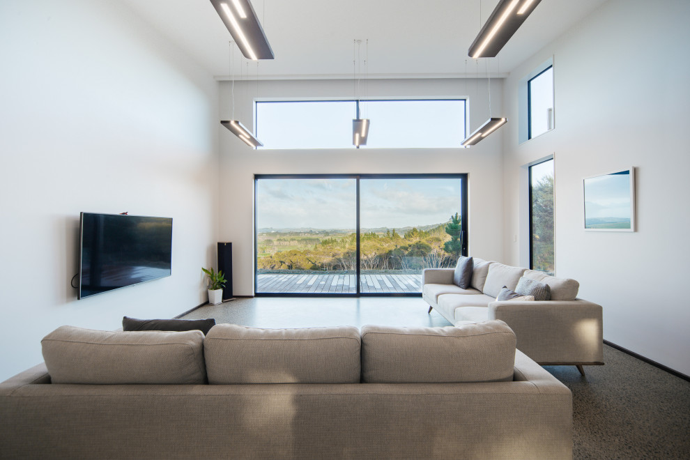 This is an example of a Mid-sized modern Open Concept living room in Auckland With White Walls, Concrete Floors, a Wall-mounted TV, Grey Floor and Vaulted.