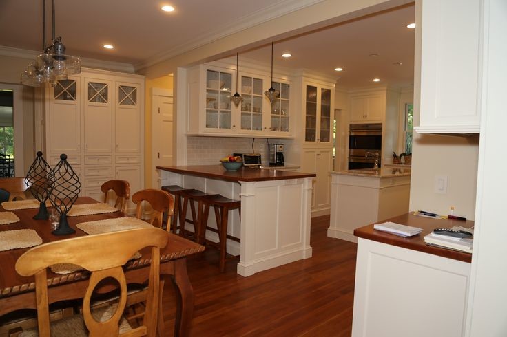 Mid-sized traditional u-shaped eat-in kitchen in Boston with white cabinets, white splashback, subway tile splashback, medium hardwood floors, an undermount sink, recessed-panel cabinets, marble benchtops, stainless steel appliances, multiple islands and brown floor.