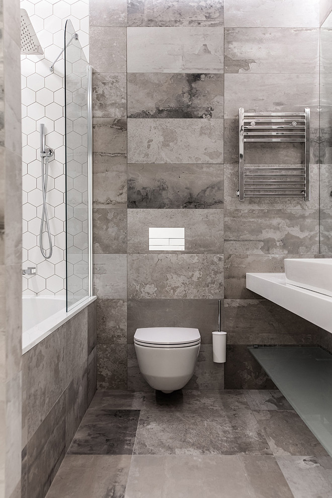 На фото: главная ванная комната среднего размера с ванной в нише, душем над ванной, инсталляцией, серой плиткой, керамогранитной плиткой, серыми стенами, полом из керамогранита, накладной раковиной, серым полом и шторкой для ванной