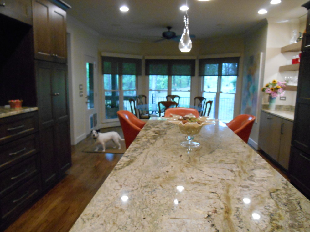 Example of a mid-sized transitional l-shaped medium tone wood floor eat-in kitchen design in Birmingham with a single-bowl sink, flat-panel cabinets, medium tone wood cabinets, granite countertops, stone slab backsplash, paneled appliances, beige walls and an island