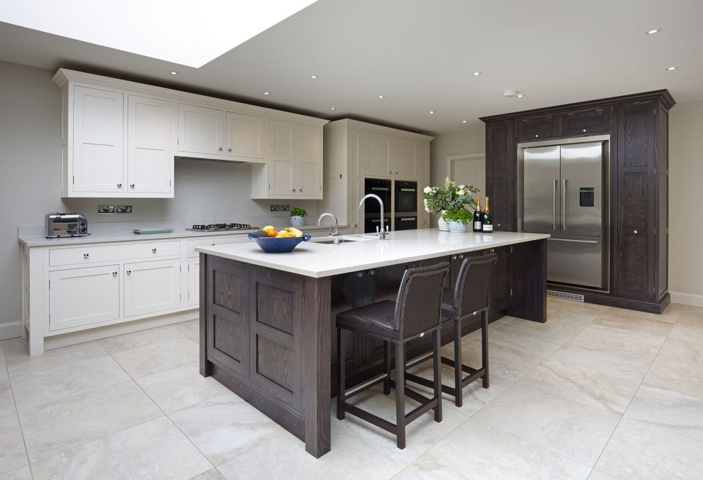 Design ideas for a large traditional single-wall open plan kitchen in London with a drop-in sink, shaker cabinets, dark wood cabinets, marble benchtops, white splashback, stone tile splashback, stainless steel appliances, ceramic floors and with island.