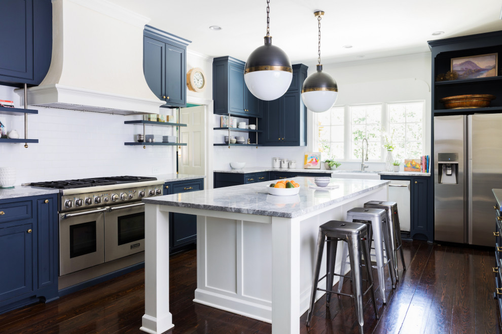 This is an example of a transitional u-shaped kitchen in Atlanta with a farmhouse sink, beaded inset cabinets, blue cabinets, white splashback, stainless steel appliances, dark hardwood floors, brown floor and white benchtop.
