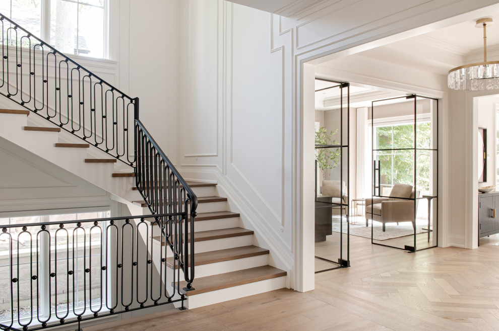 Staircase - large transitional wooden u-shaped metal railing and wall paneling staircase idea in Toronto with wooden risers