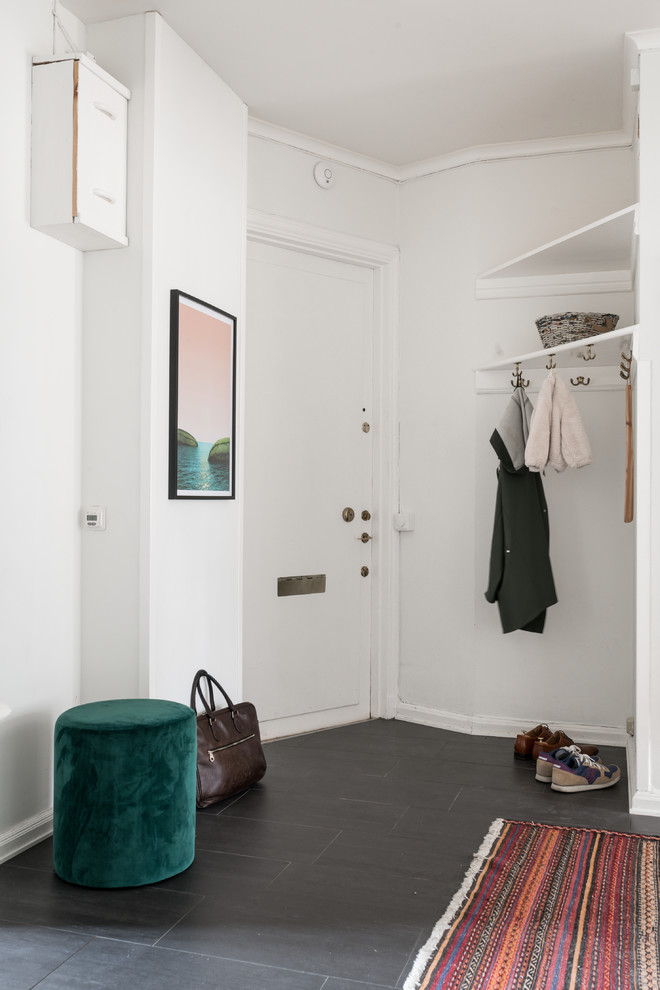 This is an example of a scandinavian foyer in Stockholm with a single front door, a white front door, grey floor and white walls.