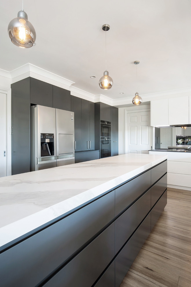 Design ideas for a large contemporary u-shaped open plan kitchen in Sydney with a double-bowl sink, flat-panel cabinets, white cabinets, tile benchtops, grey splashback, glass sheet splashback, stainless steel appliances, medium hardwood floors, with island, brown floor and white benchtop.