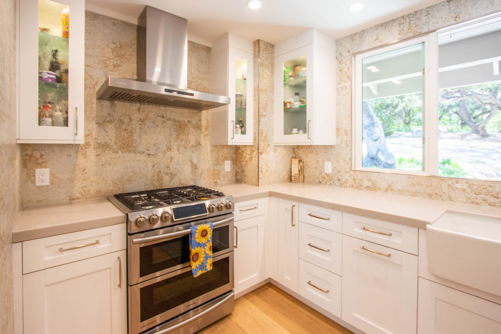 Inspiration for a transitional l-shaped light wood floor and brown floor eat-in kitchen remodel with a farmhouse sink, shaker cabinets, white cabinets, quartz countertops, porcelain backsplash, stainless steel appliances and an island