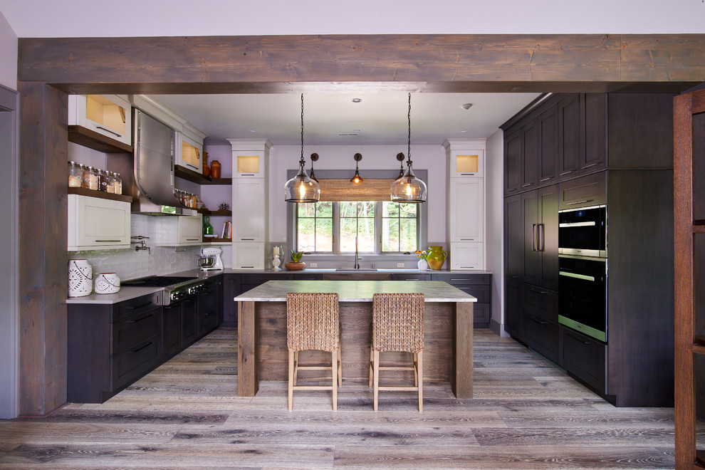 Example of a transitional u-shaped dark wood floor and gray floor kitchen design with an undermount sink, recessed-panel cabinets, white cabinets, quartzite countertops, white backsplash, ceramic backsplash, stainless steel appliances, an island and gray countertops