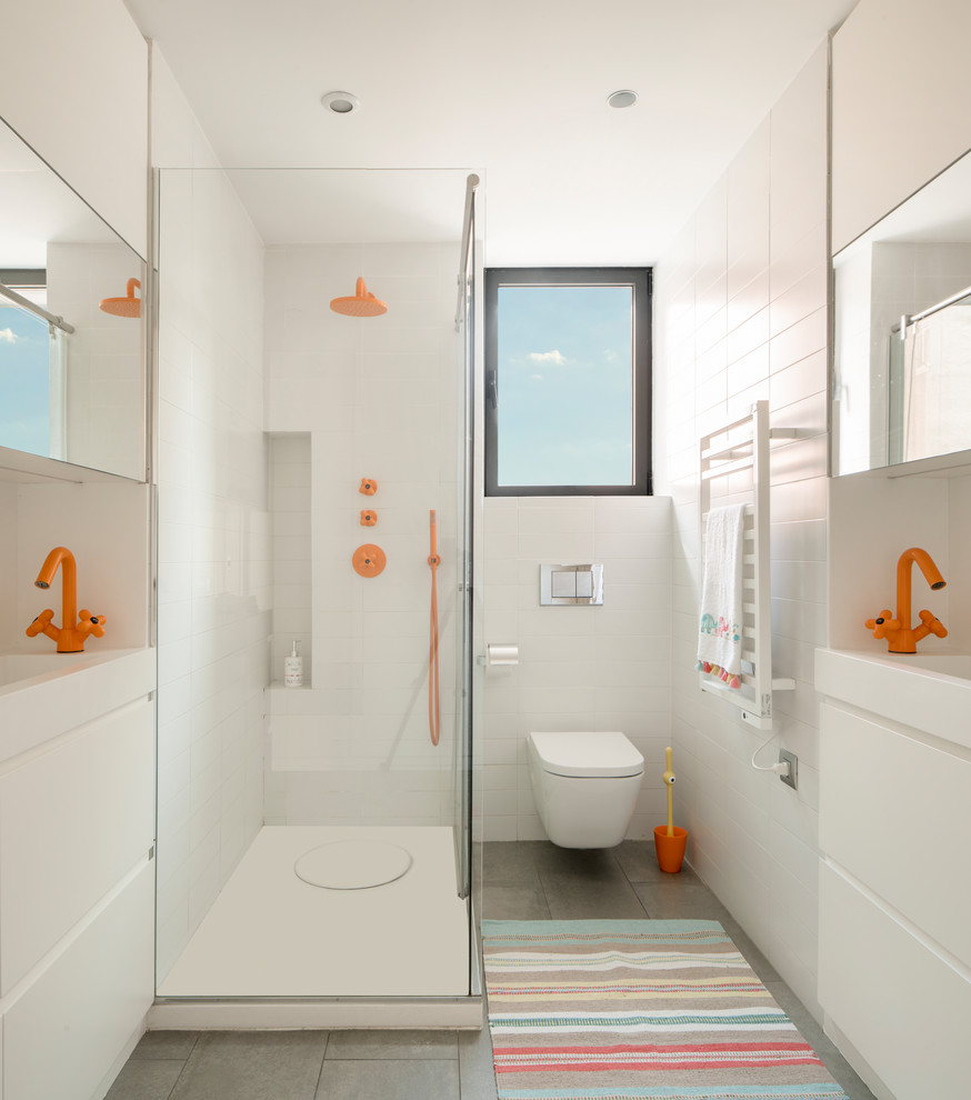 This is an example of a large contemporary kids bathroom in Barcelona with white cabinets, a freestanding tub, a one-piece toilet, gray tile, ceramic tile, white walls, ceramic floors, a wall-mount sink, solid surface benchtops, grey floor, an open shower, white benchtops and flat-panel cabinets.