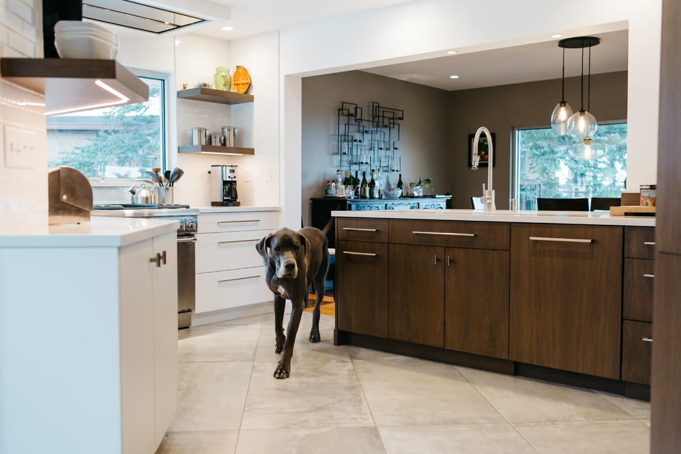 Inspiration for a mid-sized modern single-wall eat-in kitchen in Salt Lake City with a drop-in sink, flat-panel cabinets, dark wood cabinets, granite benchtops, white splashback, subway tile splashback, stainless steel appliances, ceramic floors and with island.