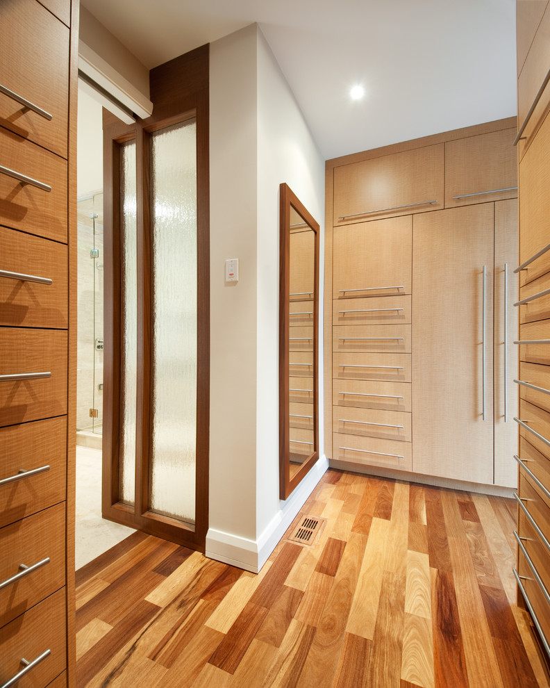 Photo of a contemporary walk-in wardrobe in Ottawa with light hardwood floors and light wood cabinets.