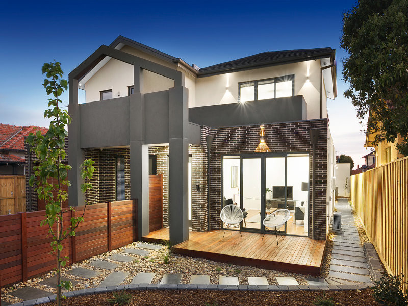 This is an example of a mid-sized modern two-storey brick grey townhouse exterior in Melbourne with a gable roof and a tile roof.