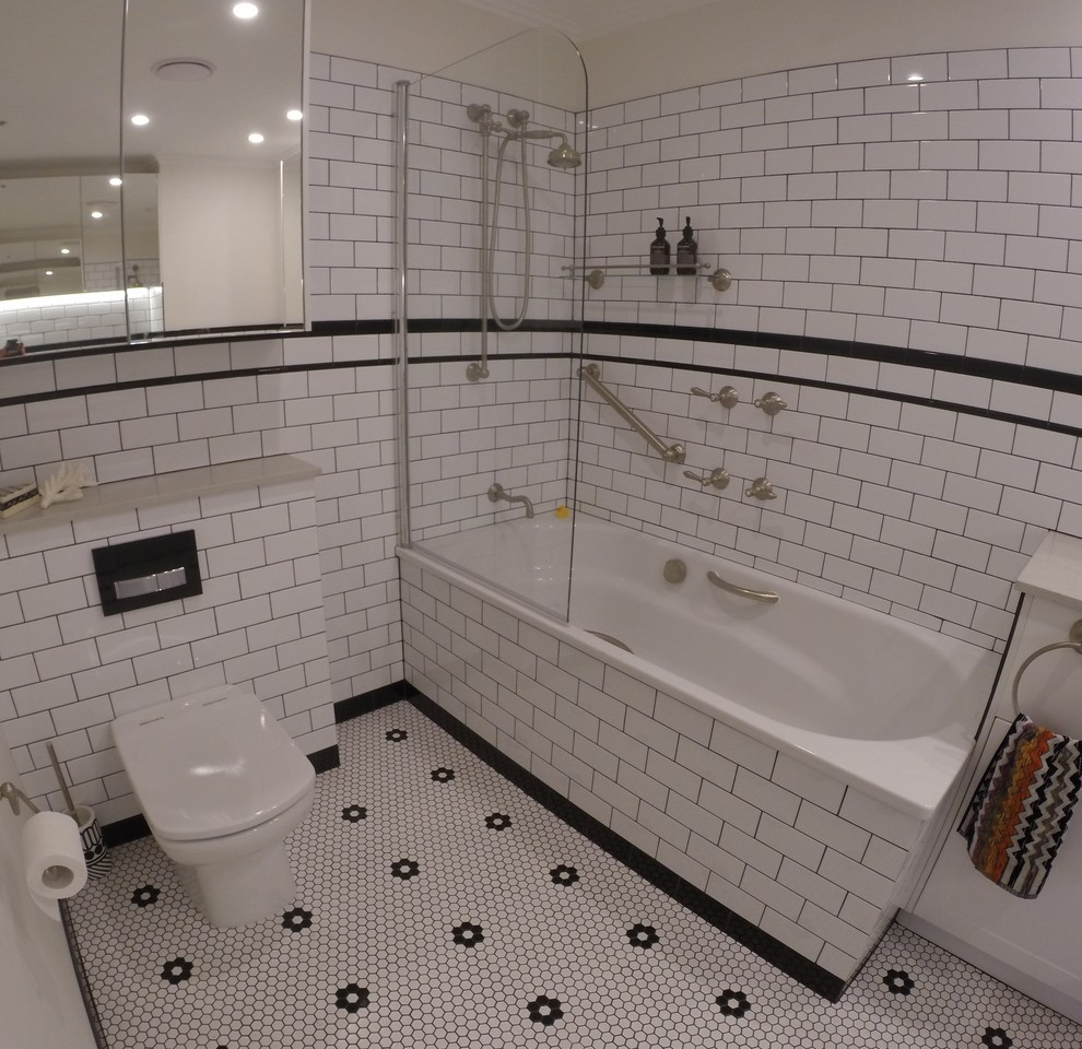 Inspiration for a mid-sized traditional kids bathroom in Melbourne with a trough sink, shaker cabinets, white cabinets, engineered quartz benchtops, a drop-in tub, a shower/bathtub combo, a one-piece toilet, white tile, ceramic tile, white walls and mosaic tile floors.