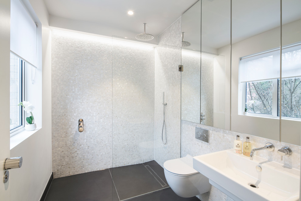 Mid-sized contemporary bathroom in London with a drop-in tub, a shower/bathtub combo, a wall-mount toilet, black and white tile, mosaic tile, brown walls, porcelain floors and a wall-mount sink.