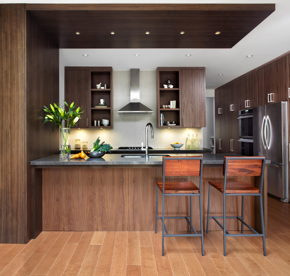 Design ideas for a mid-sized contemporary galley kitchen in Toronto with a double-bowl sink, flat-panel cabinets, dark wood cabinets, quartz benchtops, grey splashback, ceramic splashback, stainless steel appliances, medium hardwood floors and a peninsula.