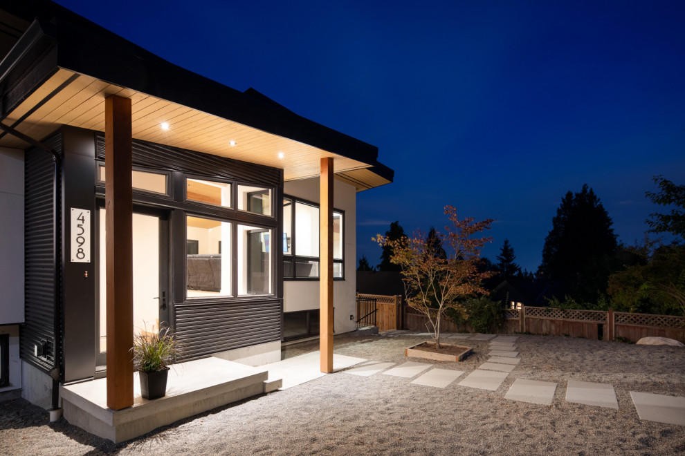 This is an example of a large contemporary house exterior in Vancouver with mixed siding and a black roof.