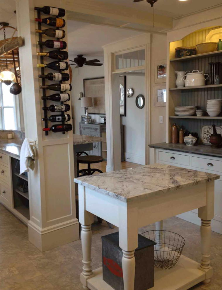 Inspiration for a large transitional l-shaped travertine floor and beige floor eat-in kitchen remodel in Boston with a farmhouse sink, recessed-panel cabinets, white cabinets, granite countertops, white backsplash, subway tile backsplash, paneled appliances, an island and black countertops