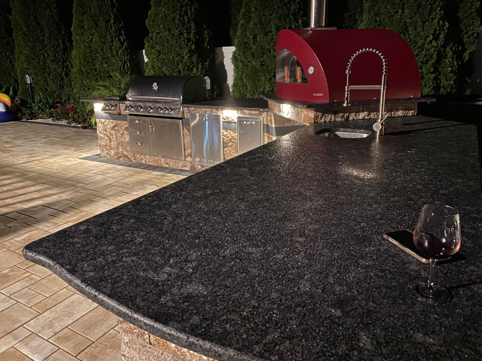 Patio kitchen - large modern backyard concrete paver patio kitchen idea in New York