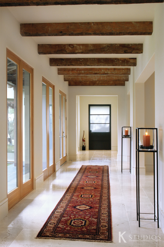 This is an example of a contemporary entry hall in Houston with white walls, travertine floors, a single front door and a black front door.