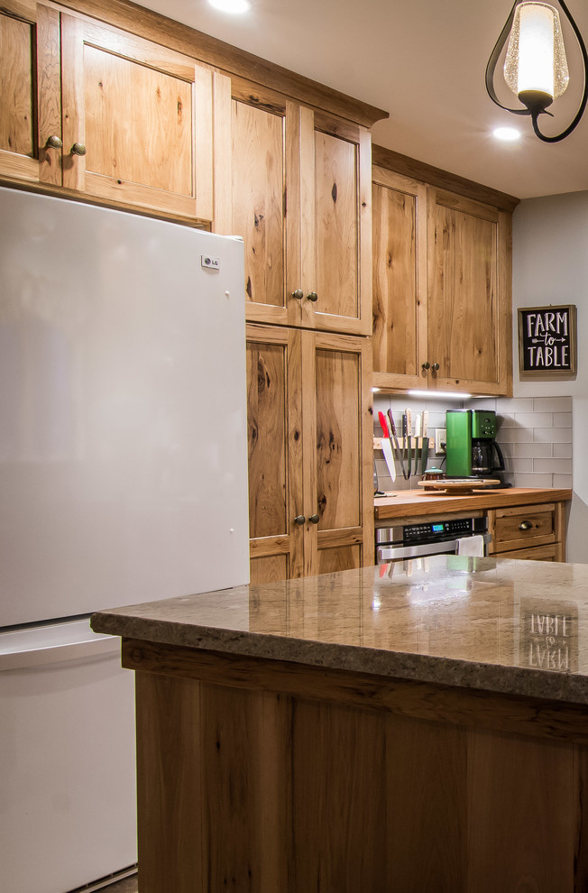 Example of a mountain style ceramic tile and beige floor kitchen design in Boston with a farmhouse sink, shaker cabinets, light wood cabinets, granite countertops, gray backsplash, subway tile backsplash and stainless steel appliances