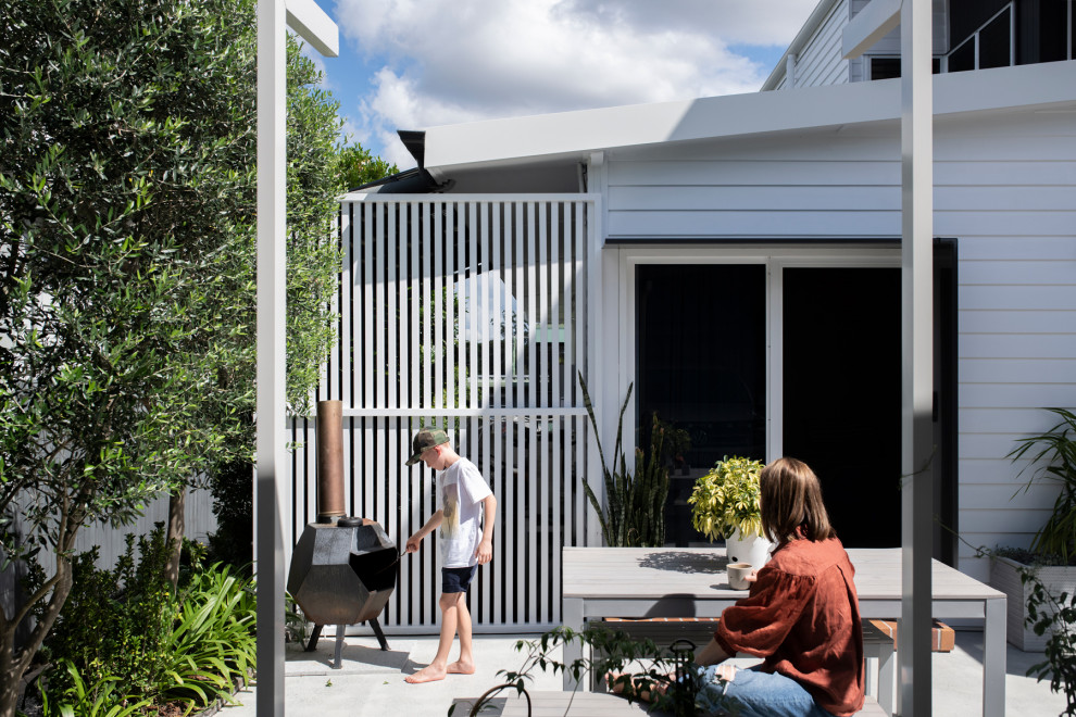 Immagine di un grande patio o portico moderno davanti casa con un caminetto, pavimentazioni in mattoni e un tetto a sbalzo