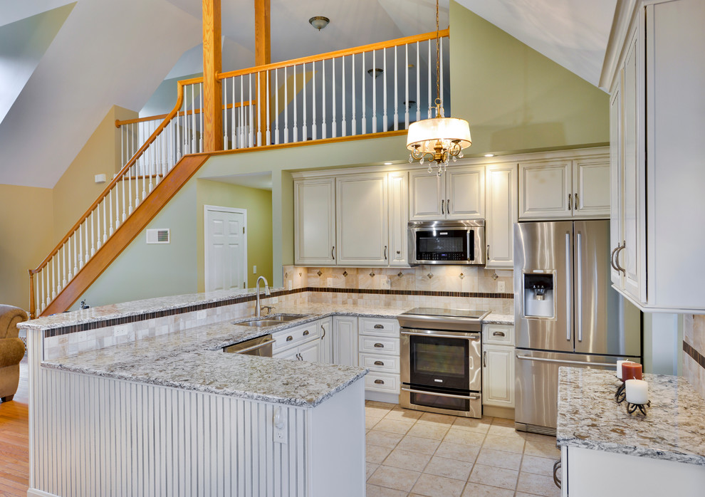 Mid-sized transitional galley open concept kitchen photo with a double-bowl sink, beaded inset cabinets, white cabinets, wood countertops, beige backsplash, ceramic backsplash, stainless steel appliances and a peninsula