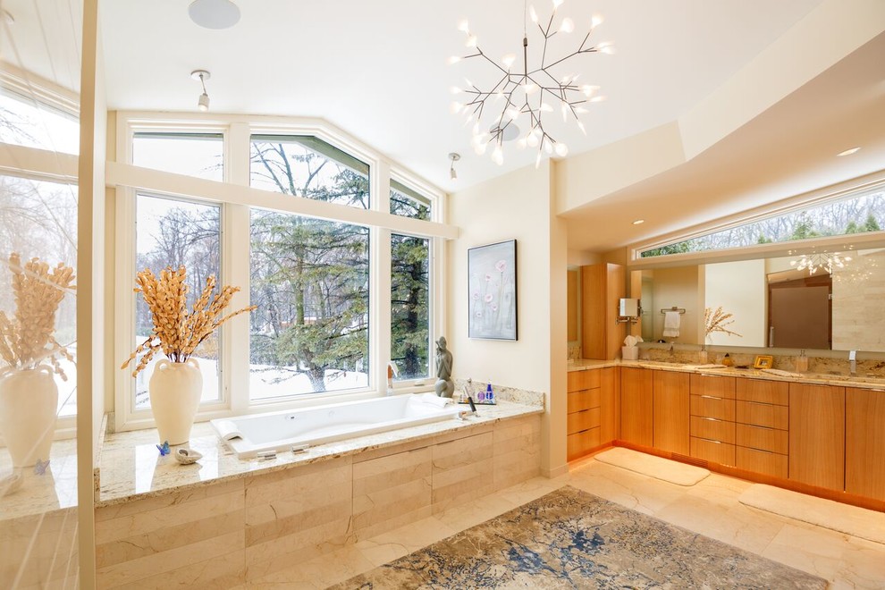 Design ideas for an expansive contemporary master bathroom in Minneapolis with flat-panel cabinets, light wood cabinets, a drop-in tub, a curbless shower, a bidet, beige tile, stone slab, white walls, travertine floors, an undermount sink and granite benchtops.