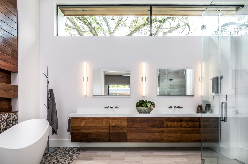 Design ideas for a contemporary master bathroom in Houston with flat-panel cabinets, dark wood cabinets, a freestanding tub, multi-coloured tile, pebble tile, white walls, pebble tile floors, multi-coloured floor, white benchtops and a hinged shower door.