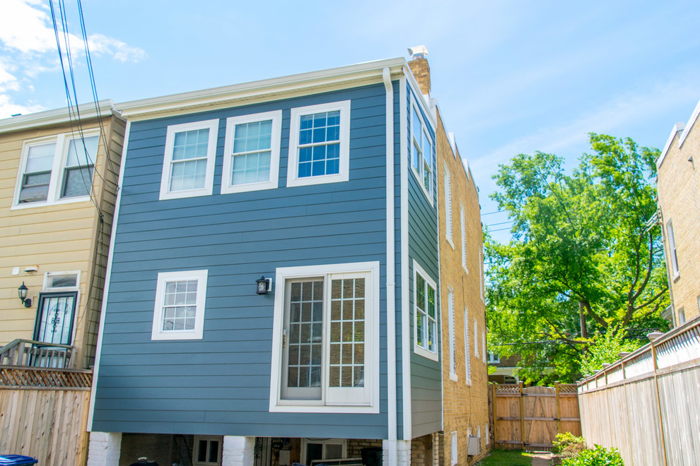 Photo of a mid-sized three-storey blue townhouse exterior in DC Metro with concrete fiberboard siding and a flat roof.