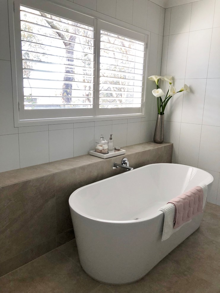 Design ideas for a large contemporary master bathroom in Other with furniture-like cabinets, brown cabinets, a freestanding tub, an open shower, white tile, ceramic tile, white walls, ceramic floors, a drop-in sink, solid surface benchtops, beige floor, an open shower and white benchtops.