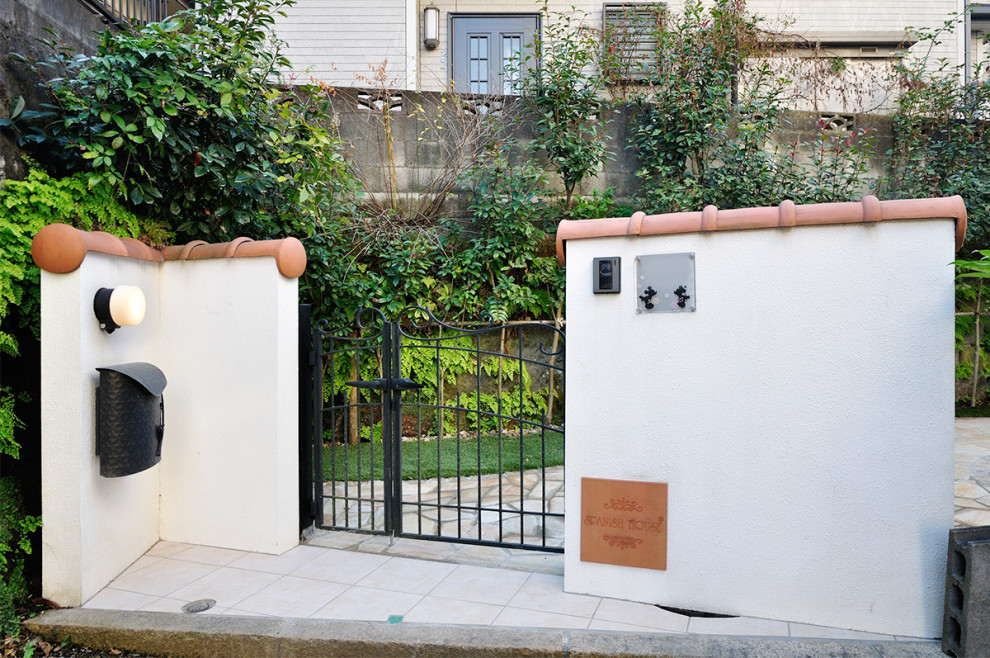 Photo of a medium sized mediterranean front garden in Yokohama with a gate, natural stone paving and a metal fence.