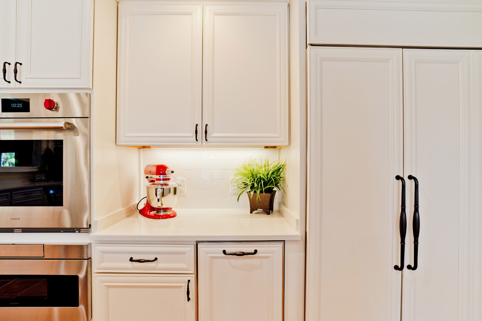 Large transitional u-shaped terra-cotta tile and orange floor eat-in kitchen photo with an undermount sink, recessed-panel cabinets, white cabinets, quartz countertops, white backsplash, subway tile backsplash, stainless steel appliances and an island