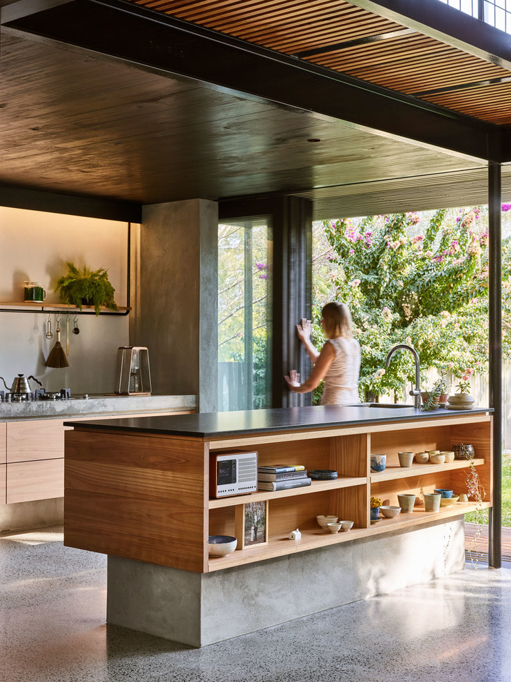 Inspiration for a small contemporary galley kitchen in Brisbane with an undermount sink, flat-panel cabinets, light wood cabinets, granite benchtops, concrete floors, with island, grey floor and black benchtop.