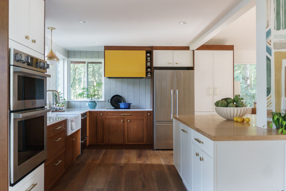Mid-sized mid-century modern u-shaped vinyl floor and vaulted ceiling eat-in kitchen photo in Seattle with a farmhouse sink, medium tone wood cabinets, wood countertops, stainless steel appliances and an island