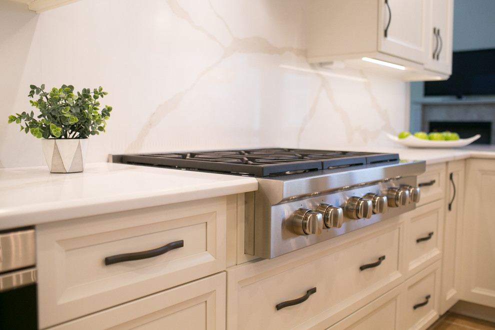 Open concept kitchen - mid-sized transitional u-shaped open concept kitchen idea in Orlando with recessed-panel cabinets, white cabinets, quartzite countertops, white backsplash, stone slab backsplash, stainless steel appliances and a peninsula