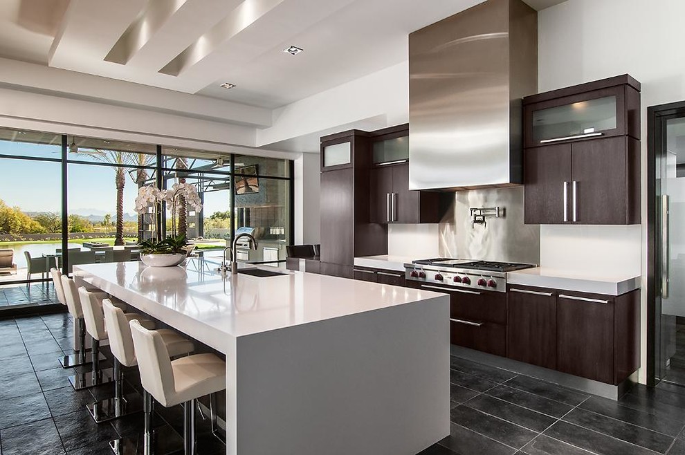 Photo of a contemporary galley kitchen in Los Angeles with an undermount sink, flat-panel cabinets, dark wood cabinets, metallic splashback, stainless steel appliances and with island.