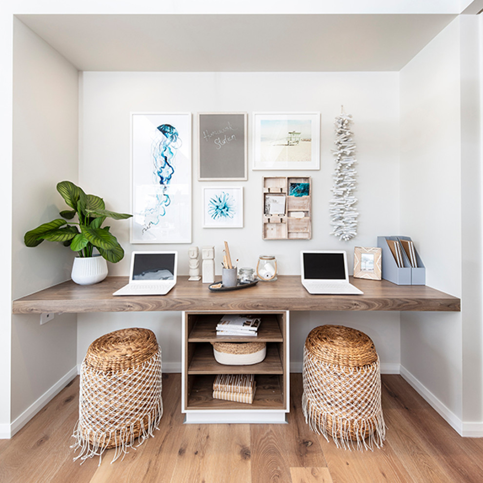 Photo of a small beach style study room in Other with white walls, medium hardwood floors, a built-in desk and brown floor.