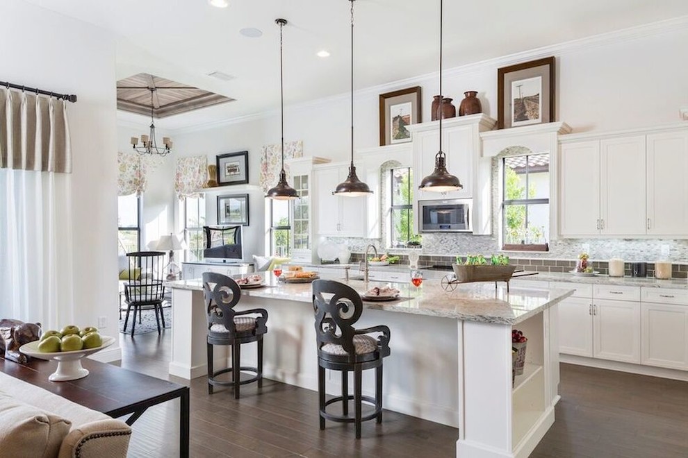 Example of a large transitional l-shaped dark wood floor open concept kitchen design in Miami with shaker cabinets, an island, white cabinets, granite countertops, gray backsplash, matchstick tile backsplash, stainless steel appliances and a farmhouse sink