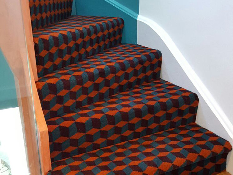 Mid-sized modern carpeted curved staircase in London with carpet risers and mixed railing.